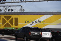 Vehicles wait for a Brightline passenger train to pass on Wednesday, Nov. 27, 2019, in Oakland Park, Fla. After Richard Branson announced his Virgin Group would partner with Brightline, Florida's new higher-speed passenger rail service, a train whisked the British billionaire, VIPs and journalists from Miami to West Palm Beach in just over an hour and then back, with no problems. (AP Photo/Brynn Anderson)