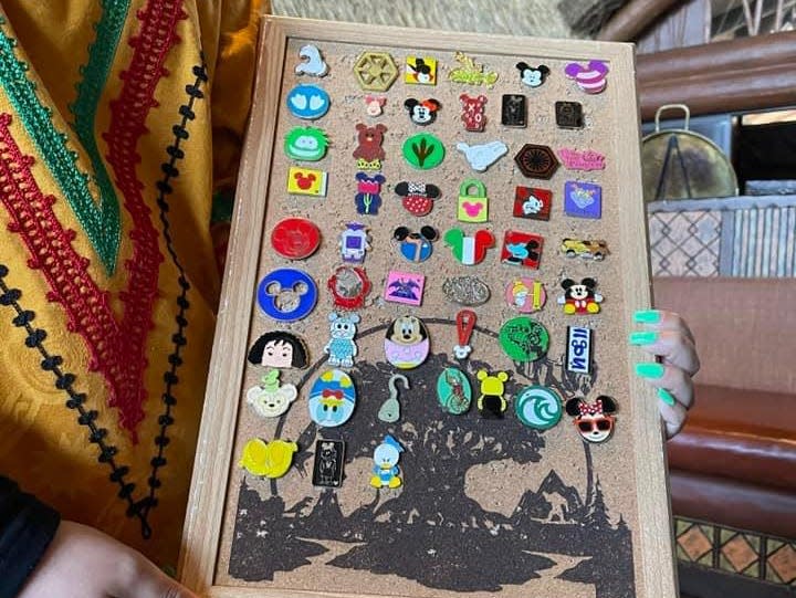 cast member at disney world holding a pin board for pin trading