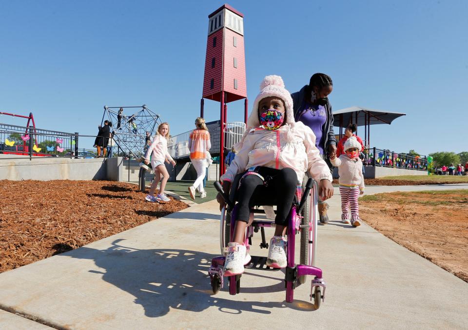 The All Inclusive Playground at Sokol Park opened and was christened Mason's Place Wednesday, April 21, 2021, in Tuscaloosa. Zaria Curry runs her wheelchair down to a round about ride as her mother, Larrenda Curry, follows with Jezana Curry. [Staff Photo/Gary Cosby Jr.]