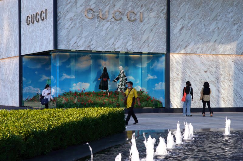 FILE PHOTO: People wearing face masks following the COVID-19 outbreak walk past a store of Italian luxury brand Gucci at a shopping complex in Beijing