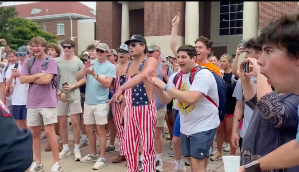 <span>A group of dozens of young white men and women, laughing and with hands raised, with two men wearing no shirt under coveralls designed like the American flag.</span><span>Photograph: Stacey J Spiehler/AP</span>