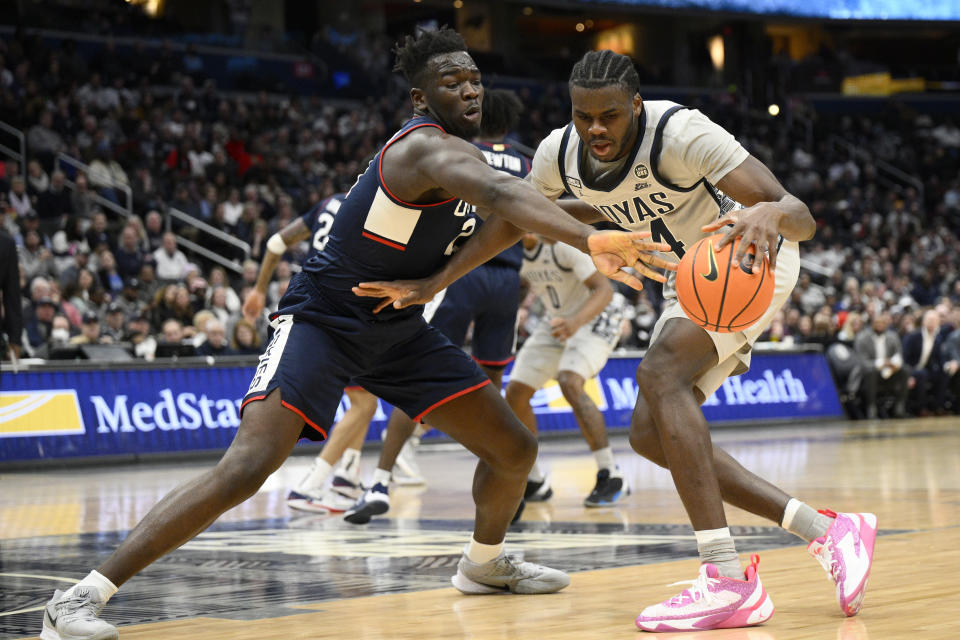 Connecticut forward Adama Sanogo, left, reaches for the ball against Georgetown center Qudus Wahab, right, during the second half of an NCAA college basketball game, Saturday, Feb. 4, 2023, in Washington. Connecticut won 68-62. (AP Photo/Nick Wass)