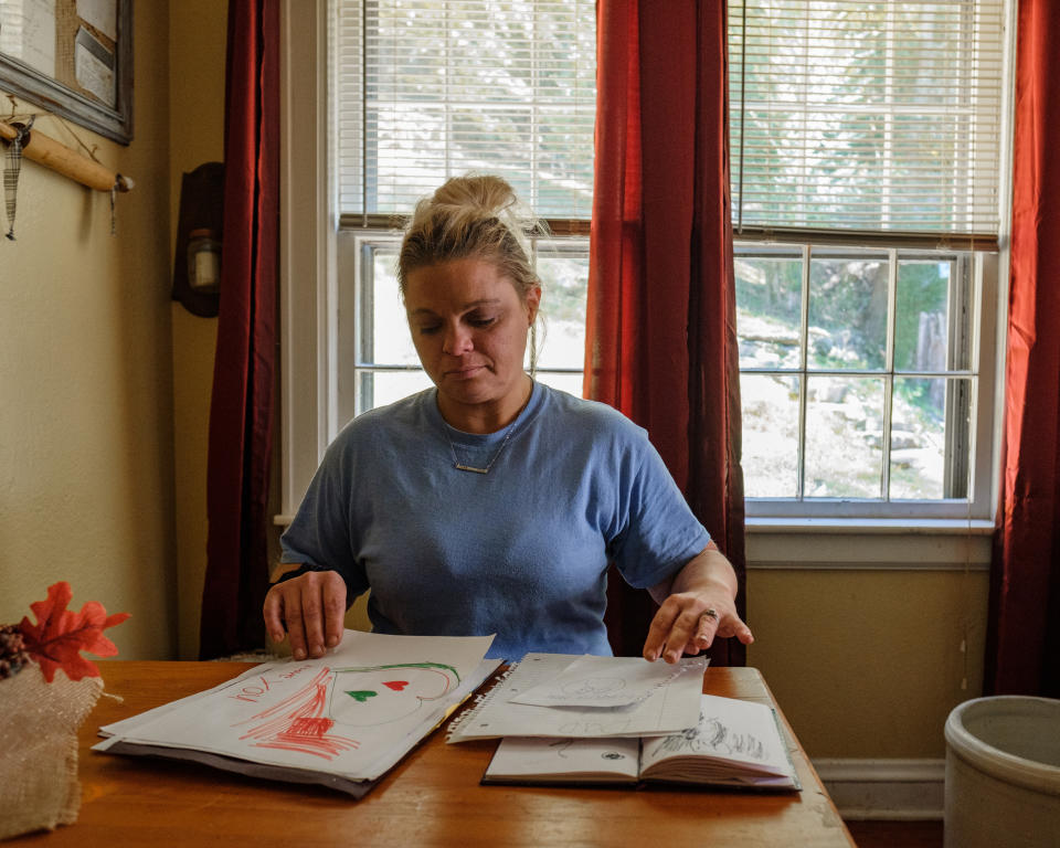 Jackie Snodgrass sitting in her dining room looking at notes and drawings made by her daughers (Stephanie Mei-Ling for NBC News and ProPublica)