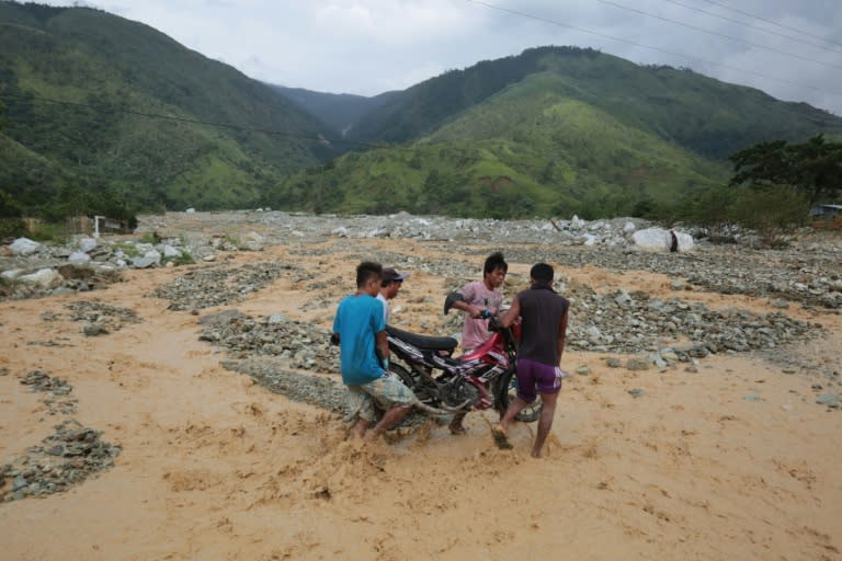 Residents carry a motorbike along a destroyed highway following heavy rains brought by Typhoon Sarika in the town of Gabaldon, Philippines on October 16, 2016