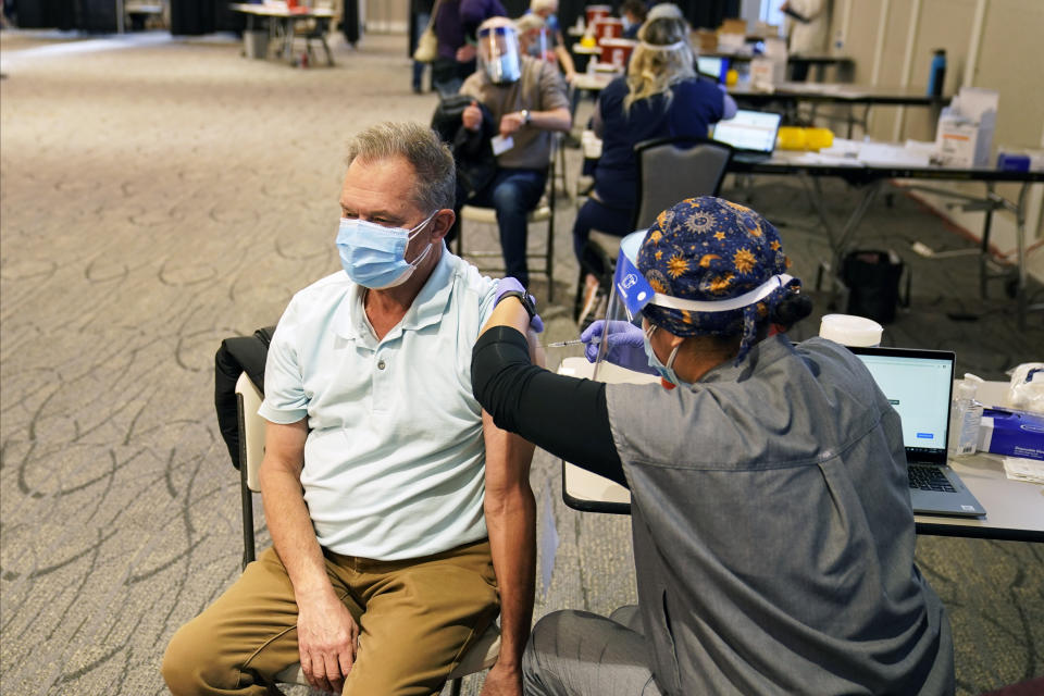 Ron Tupy receives a vaccination, Thursday, Jan. 21, 2021 at the Earle Brown Heritage Center in Brooklyn Center, Minn. Minnesota on Thursday opened up nine locations for coronavirus vaccinations as part of a pilot program reserved for people 65 and over. Demand for the program was exceptionally heavy, with slots for the few available doses quickly filling after registration opened two days earlier. (AP Photo/Jim Mone)