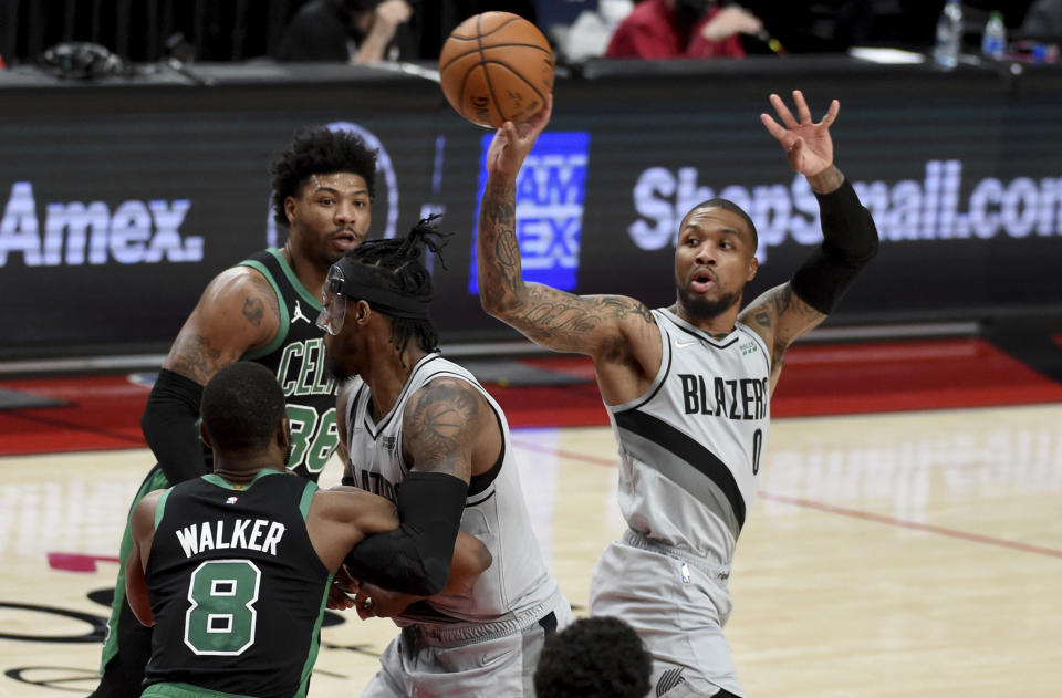 Portland Trail Blazers guard Damian Lillard, right, passes the ball over Boston Celtics guard Kemba Walker, left, during the second half of an NBA basketball game in Portland, Ore., Tuesday, April 13, 2021. (AP Photo/Steve Dykes)