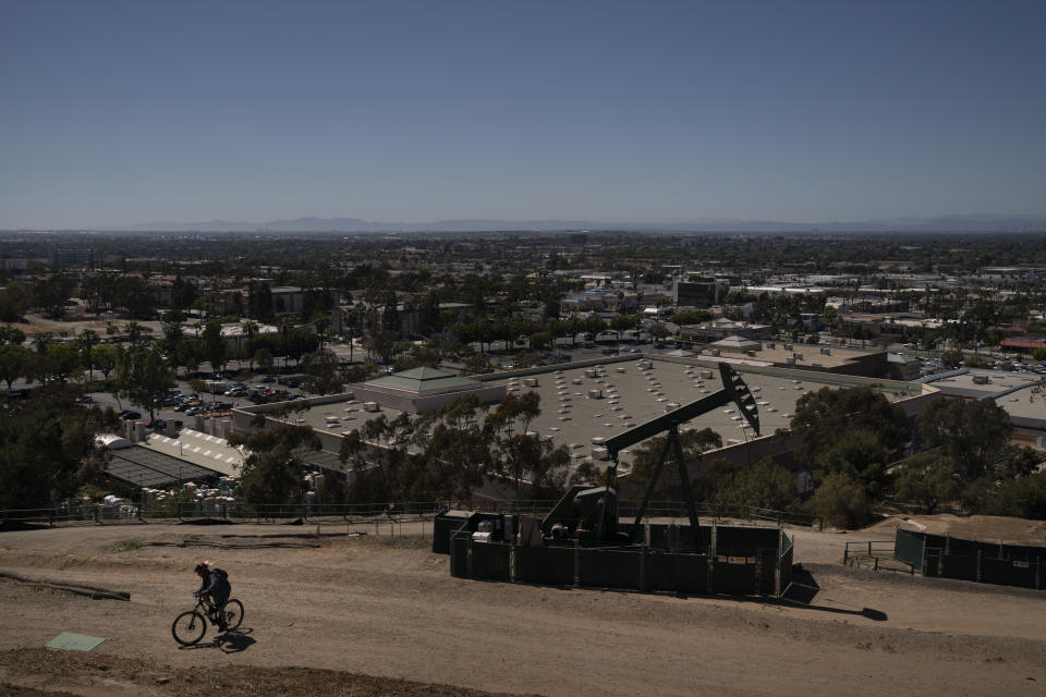 FILE - A man rides his bike past an oil pump jack Wednesday, June 9, 2021, in Signal Hill, Calif. Residents in several regions of California allege that they’ve been misled by signature gatherers over the last two months as a campaign, Stop the Energy Shutdown, pushed to gather enough signatures to get a referendum to overturn SB 1137 on the 2024 statewide ballot. SB 1137, a law passed to ban new oil and gas wells within 3,200 feet (975 meters) of schools, homes and hospitals, was signed into law by California Gov. Newsom in September. (AP Photo/Jae C. Hong, File)