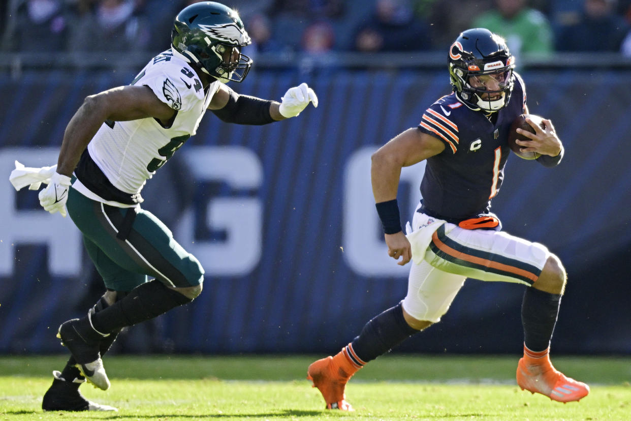 CHICAGO, ILLINOIS - DECEMBER 18: Justin Fields #1 of the Chicago Bears runs the ball while being chased by Josh Sweat #94 of the Philadelphia Eagles during the first half at Soldier Field on December 18, 2022 in Chicago, Illinois. (Photo by Quinn Harris/Getty Images)