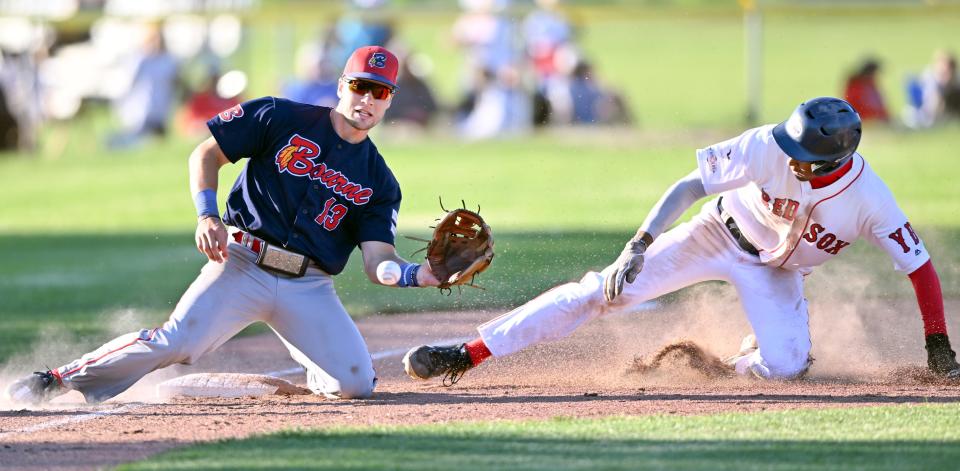 Bourne Braves third baseman Wyatt Henseler (left) waits to catch a throw as Homer Bush Jr. of the Y-D Red Sox arrives safely at third base in a Cape League Baseball League game in South Yarmouth, Mass., on June 21, 2022