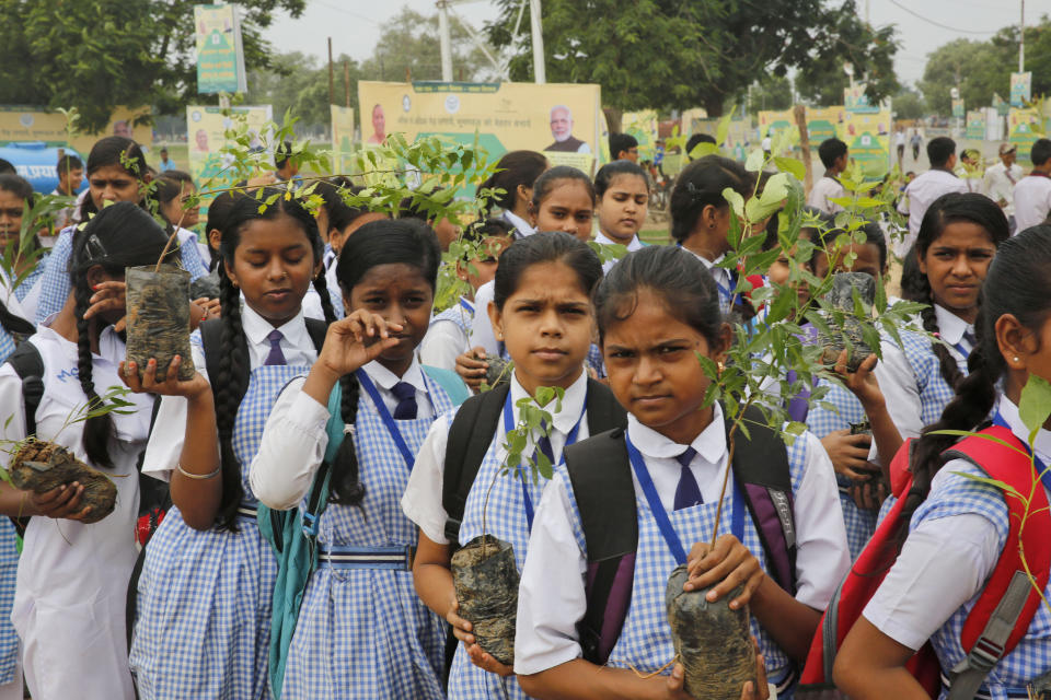 Indian school children hold saplings distributed by the government in Prayagraj, India , Friday, Aug. 9, 2019. More than a million Indians planted saplings as part of a government campaign to tackle climate change and improve environment in the country’s most populated state. (AP Photo/Rajesh Kumar Singh)