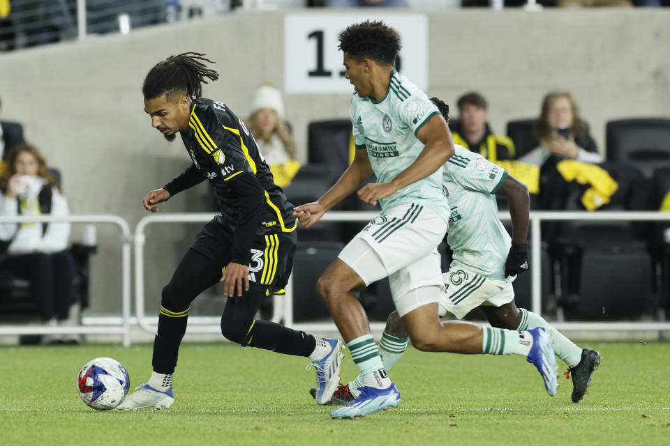 Columbus Crew's Mohamed Ramzdine Farsi, left, looks for an open pass as Atlanta United's Caleb Wiley, front right, defends and during the second half of an MLS playoff soccer match Sunday, Nov. 12, 2023, in Columbus, Ohio. (AP Photo/Jay LaPrete)