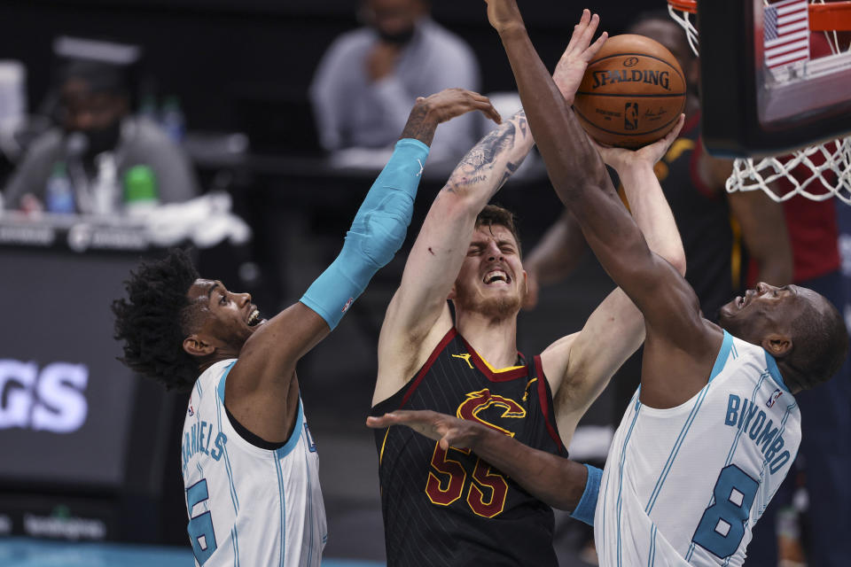 Cleveland Cavaliers center Isaiah Hartenstein, center, shoots between Charlotte Hornets forward Jalen McDaniels, left, and center Bismack Biyombo (8) during the second quarter of an NBA basketball game in Charlotte, N.C., Wednesday, April 14, 2021. (AP Photo/Nell Redmond)