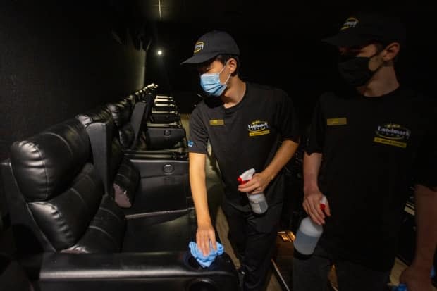 Yunny Kim, left, and Thorin Shaver wear face masks while cleaning a movie theatre in Kingston, Ont., in mid-July. (Lars Hagberg/The Canadian Press - image credit)