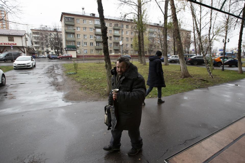 In this photo taken on Sunday, Nov. 3, 2019, a homeless man hold a hot coffee as walks in a street in Liublino, a working class suburb in Moscow, Russia. Moscow’s suburbs are the focus of a major international art exhibition that has just opened in the Russian capital. The exhibit uses contemporary art to explore the many hidden facets of life beyond the Russian capital’s nucleus. Austrian cultural attache says the ‘real’ Moscow where most of the city’s 12.6 million people live, is outside the center. (AP Photo/Alexander Zemlianichenko)