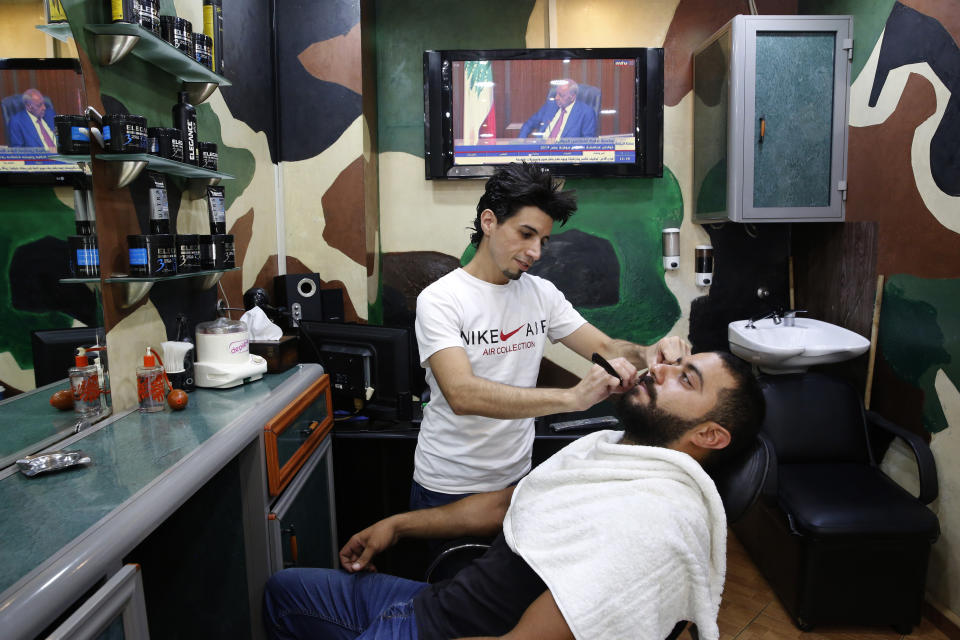 In this Thursday, July 18, 2019 photo, Mohammed Badran a Lebanese barber, works in his shop, in Beirut, Lebanon. As the economic crisis deepens in Lebanon, so has the public’s distrust in the ability of the old political class, widely viewed as corrupt and steeped in personal rivalries, to tackle major reform. Many fear a Greek-style bankruptcy, without the European Union to fall back on, and with a potentially more violent social unrest in the small country wedged between war-torn Syria and Israel. (AP Photo/Hussein Malla)