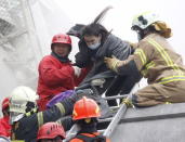 Rescue personnel help a victim at the site where a 17 story apartment building collapsed from an earthquake in Tainan, southern Taiwan, February 6, 2016. REUTERS/Pichi Chuang