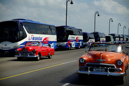 Vintage cars pass by a fleet of Chinese-made Yutong buses parked at the sea front Malecon in Havana, Cuba, February 10, 2017. REUTERS/Alexandre Meneghini