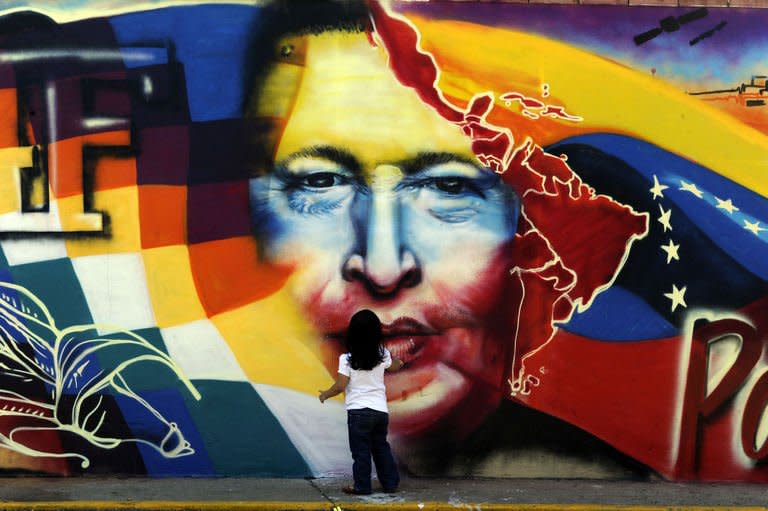 A child stands in front of a graffitti at the Mountain Barracks (Cuartel de la Montana) where the remains of late Venezuelan President Hugo Chavez are staying, in the 23 de Enero low income neighborhood in Caracas, on March 28, 2013