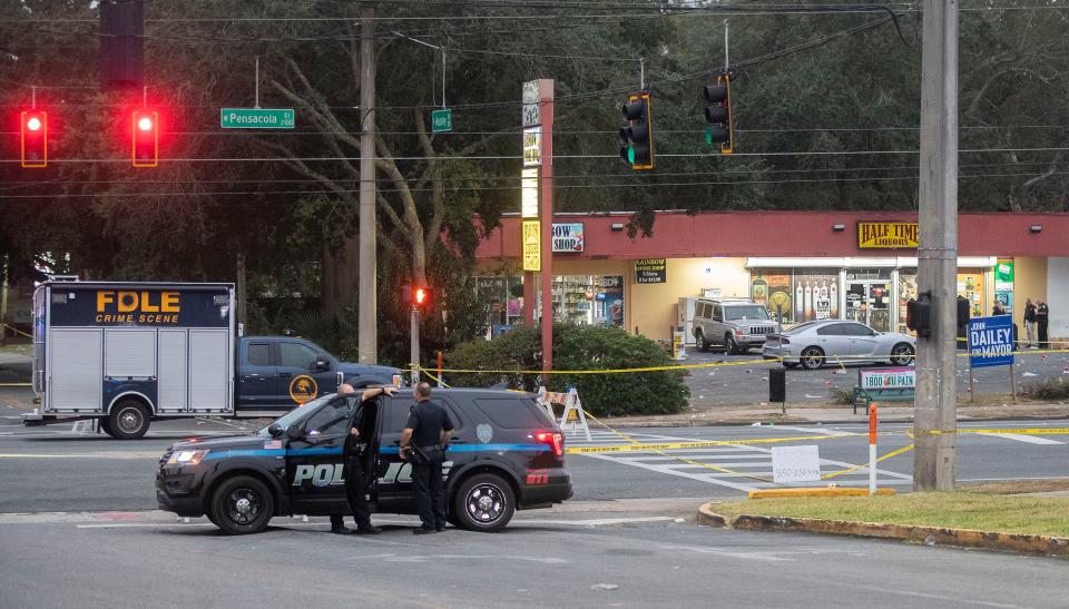 Police work in front of Half Time Liquors on Pensacola Street following a shooting Saturday night that killed at least one person and injured eight.