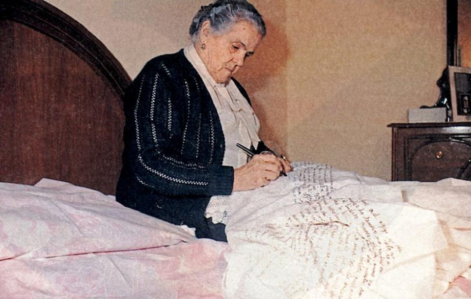 Clelia escribiendo en una sábana en su cama