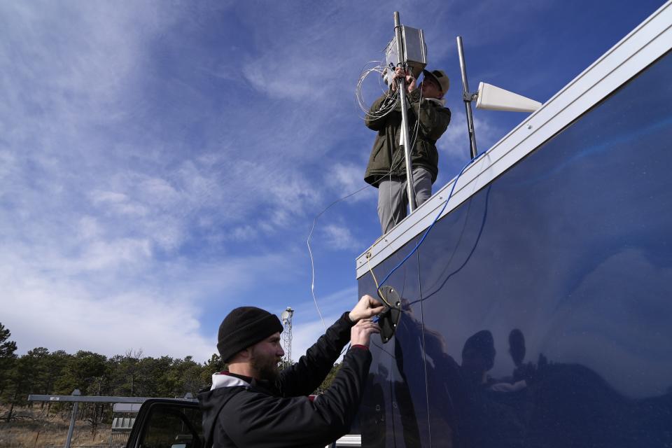 Brothers Parker, left, and Carver Cammans install cloud seeding equipment Saturday, Dec. 3, 2022, in Lyons, Colo. The technique to get clouds to produce more snow is being used more as the Rocky Mountain region struggles with a two-decade drought. (AP Photo/Brittany Peterson)