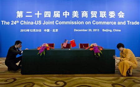 An usher and a hostess prepare a table for a signing ceremony after a meeting of the 24th China-U.S. Joint Commission on Commerce and Trade at the Diaoyutai State Guesthouse in Beijing, December 20, 2013. REUTERS/Alexander F. Yuan/Pool