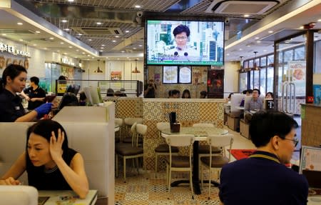 People sit at a restaurant as a news conference of Hong Kong Chief Executive Carrie Lam is broadcasted in TV in Hong Kong