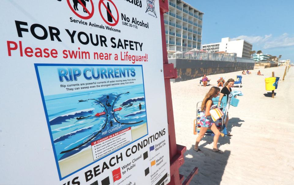 Beachgoers walk past a unmanned Volusia County lifeguard tower covered with safety information, Thursday, Feb. 2, 2023, in front of Andy Romano Beachfront Park in Ormond Beach.