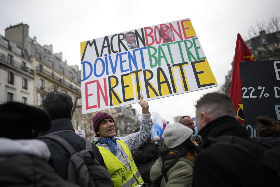 A man holds a poster reading "Macron, Borne must retire" during a demonstration, Tuesday, Jan. 31, 2023 in Paris. From tiny islands to major cities, demonstrators marched across France on Tuesday in the latest clash of wills with the government over its plans to push back the retirement age. Labor leaders aimed to bring more than 1 million protesters into the streets in what one veteran left-wing leader described as a "citizens' insurrection." (AP Photo/Christophe Ena)