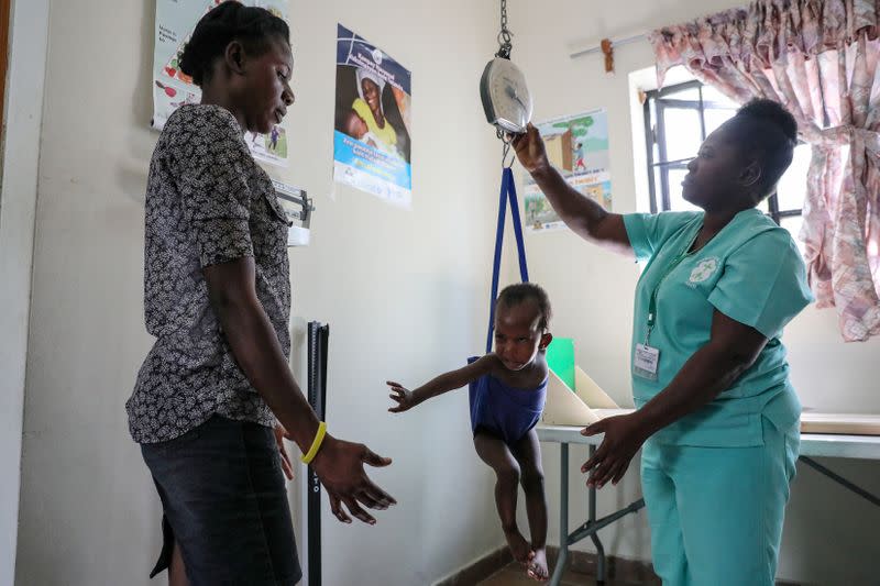 A nurse weighs a child in front of its mother at St. Luke Hospital in Port-au-Prince