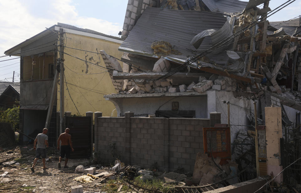 Men walk near buildings of local resort destroyed following recent Russian missile attacks in Odesa region, Ukraine, Thursday, Aug. 18, 2022. (AP Photo/Nina Lyashonok)