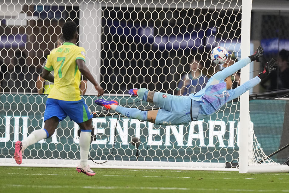 Costa Rica's goalkeeper Patrick Sequeira, right, dives for a shot on goal as Brazil's Vinicius Junior watches during a Copa America Group D soccer match Monday, June 24, 2024, in Inglewood, Calif. (AP Photo/Mark J. Terrill)