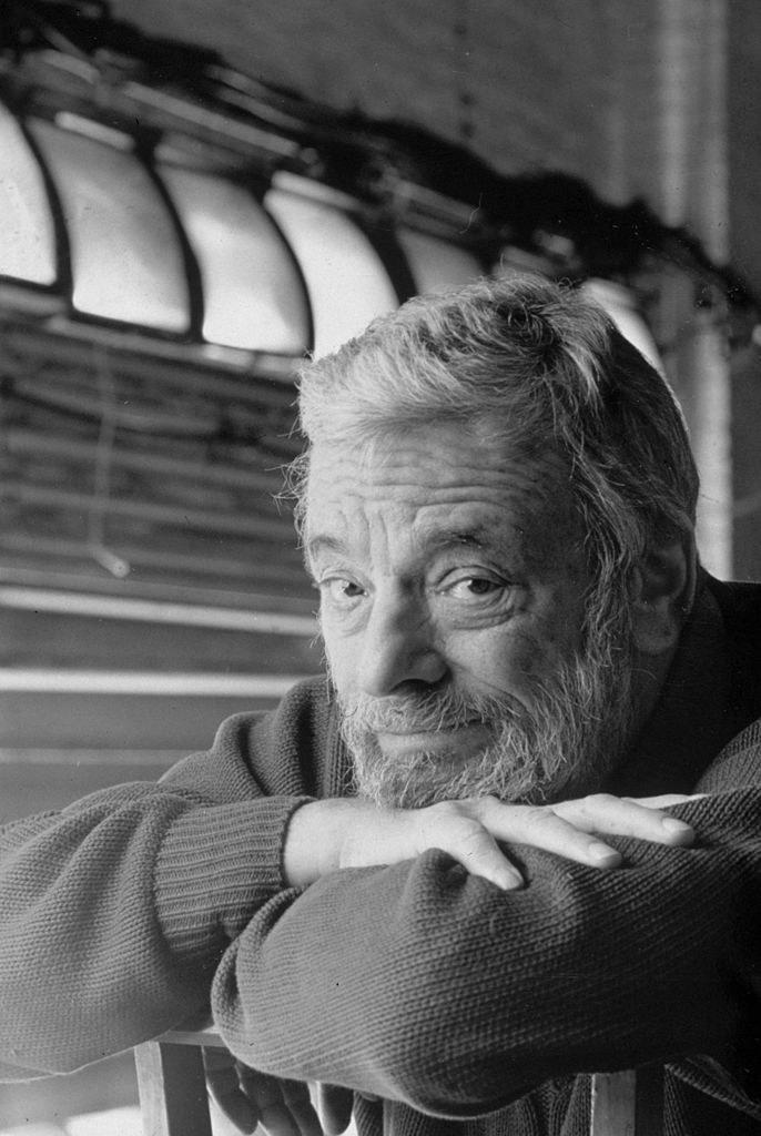 A black-and-white photo of Stephen Sondheim leaning on a chair