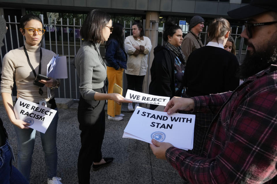 A man hands out signs as Australian Broadcasting Corp. (ABC) workers and other supporters gather at the ABC offices in Sydney, Monday, May 22, 2023, to support Indigenous journalist Stan Grant. Grant announced he would step away from television hosting duties after viewers responded with racist abuse to his comments during King Charles III's coronation about historic Aboriginal dispossession. (AP Photo/Rick Rycroft)