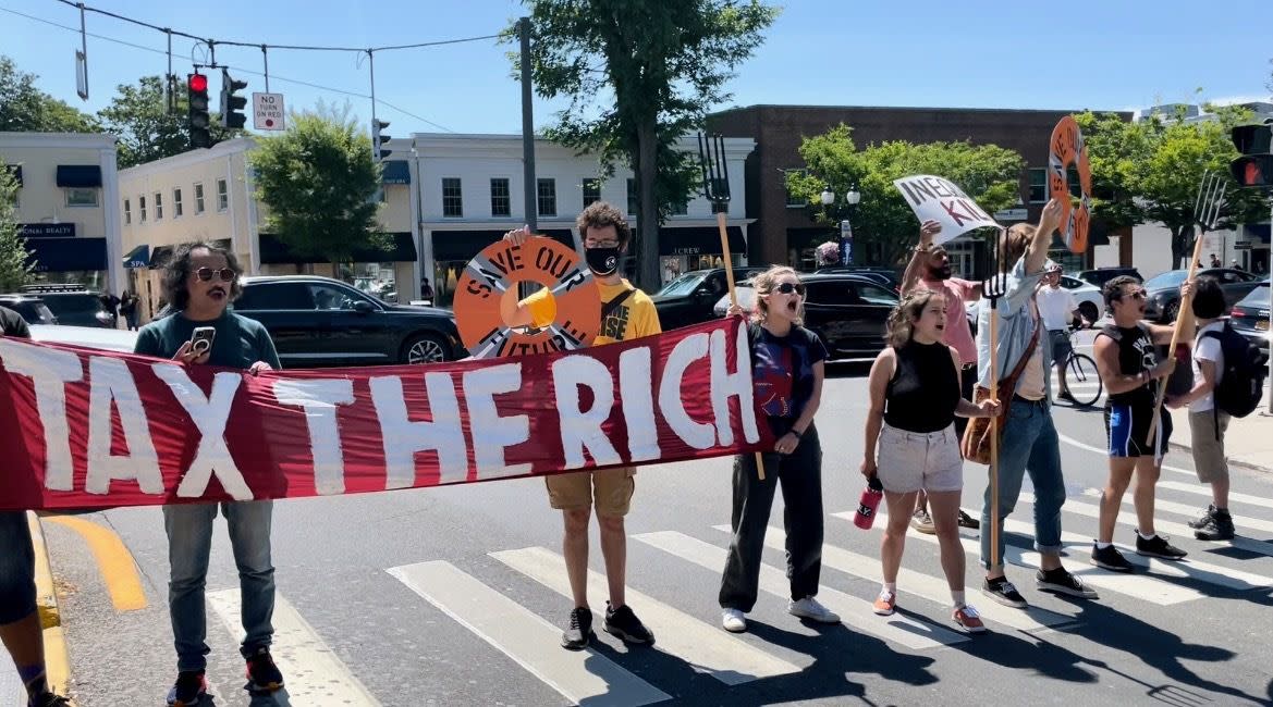 “Tax the rich, house the poor,” the crowd of protesters chanted as they linked arms at the corner of Main Street and Newtown Lane in East Hampton, New York on Monday, July 11, 2022.