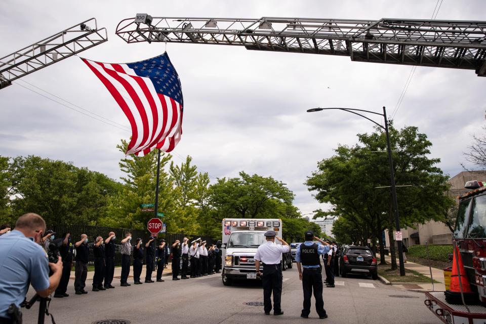 Officers salute outside the Cook County Medical Examiner's Office as an ambulance passes, containing the body of a Chicago Police officer, Tuesday, July 28, 2020, in Chicago.