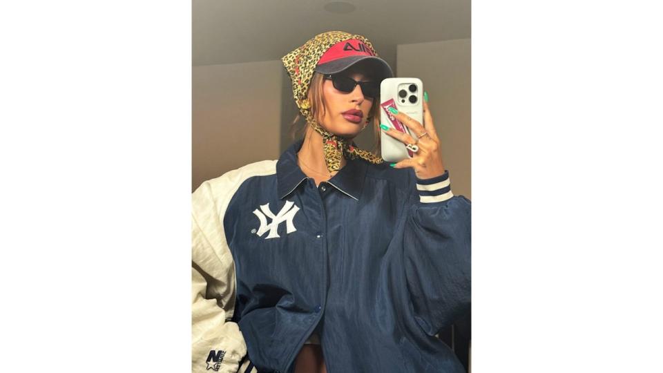 Hailey Bieber poses in a blue jacket, sunglasses, a cap and headscarf 