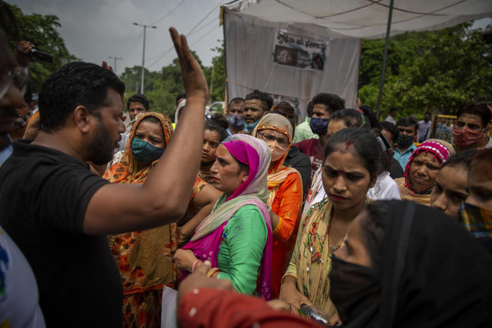 A man tries to calm protesters down as they try to block a street outside a crematorium where a 9-year-old girl from the lowest rung of India's caste system was, according to her parents and protesters, raped and killed earlier this week, in New Delhi, India, Thursday, Aug. 5, 2021. (AP Photo/Altaf Qadri)