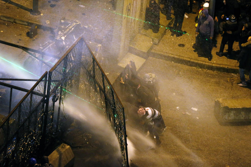 Riot police sprayed anti-government protesters with water cannons as they try to cross to the central government building during ongoing protests in Beirut, Lebanon, Saturday, Jan. 25, 2020. Hundreds of Lebanese gathered outside the central government building to reject the newly formed Cabinet, while some protesters breached tight security erected around it, removing a metal gate and barbed wire prompting a stream of water cannons from security forces. (AP Photo/Bilal Hussein)