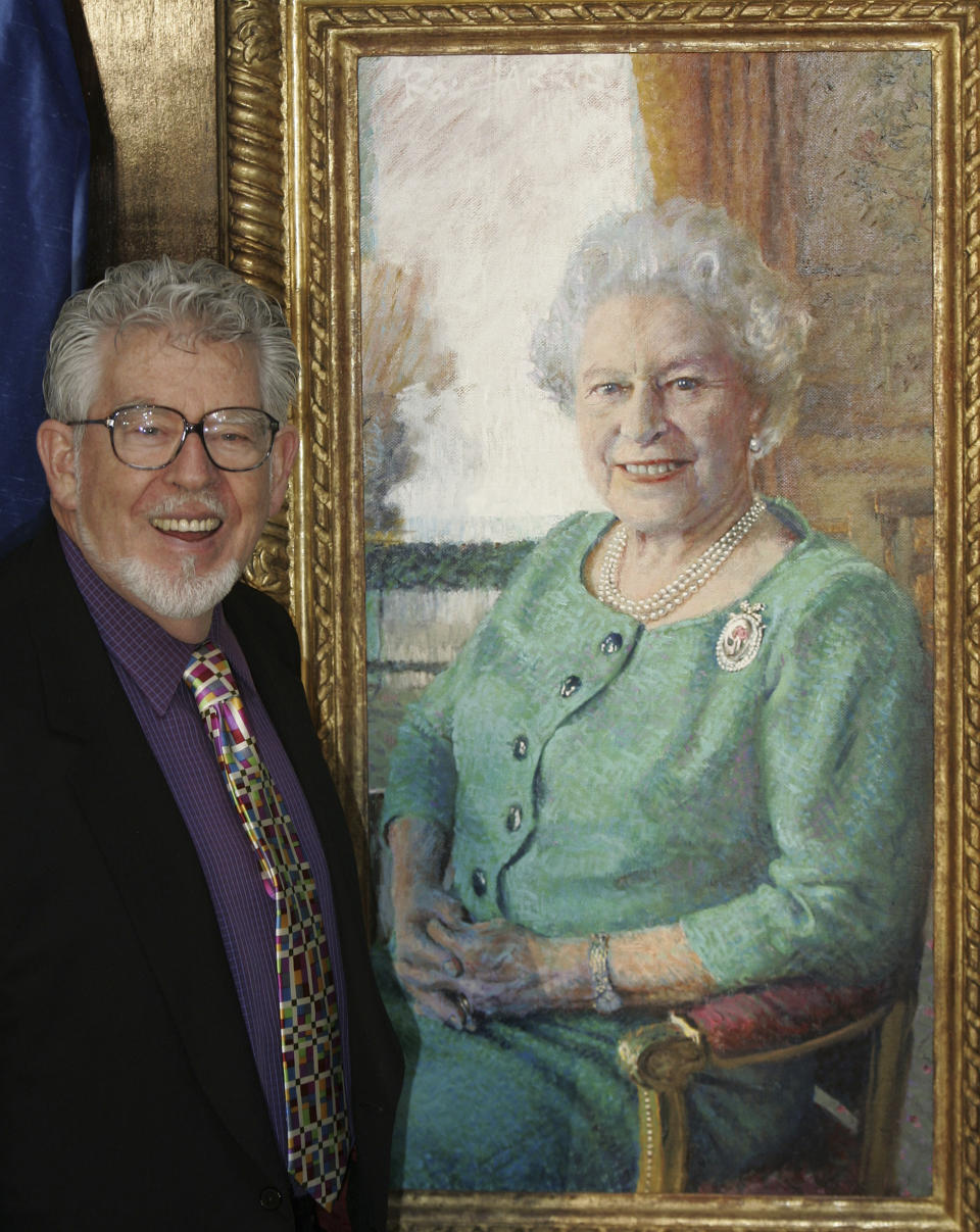 FILE - Artist Rolf Harris stands with his portrait of Britain's Queen Elizabeth II, at its unveiling at Buckingham Palace, London, Monday Dec. 19, 2005. Rolf Harris, the veteran entertainer whose decades-long career as a family favorite on British and Australian television was shattered when he was convicted of sexual assaults on young girls, has died. He was 93. (AP Photo/Kirsty Wigglesworth, File)