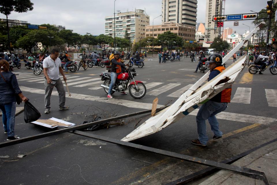 Un motociclista remueve chapas que bloquean una calle en el barrio de Altamira en Caracas, Venezuela, el lunes 24 de febrero de 2014. La capital venezolana amaneció el lunes en medio de nuevas tensiones luego de que decenas de manifestantes bloquearon algunas de las principales avenidas en protesta contra el gobierno, en medio de la crisis política que lleva tres semanas y ha dejado 14 muertos y más de un centenar de heridos.(AP foto/Rodrigo Abd)