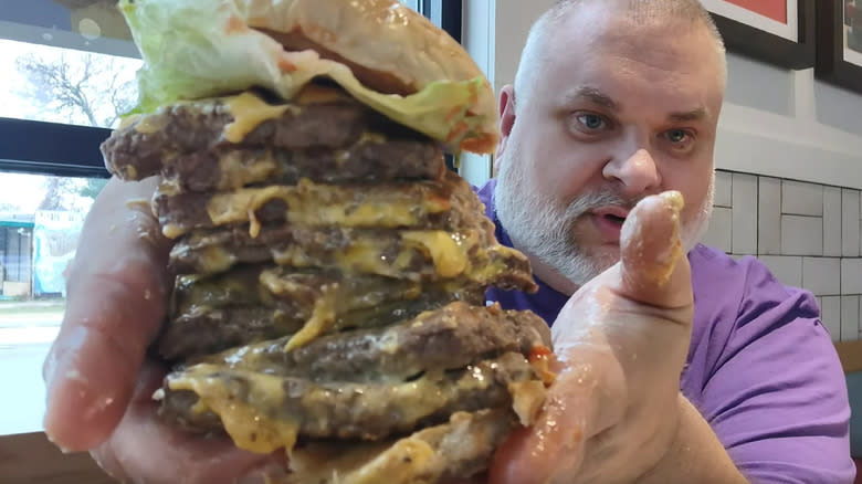 bearded man holding Wendy's T-Rex Burger