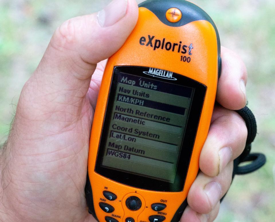 A hiker's hand with a GPS device showing their location.