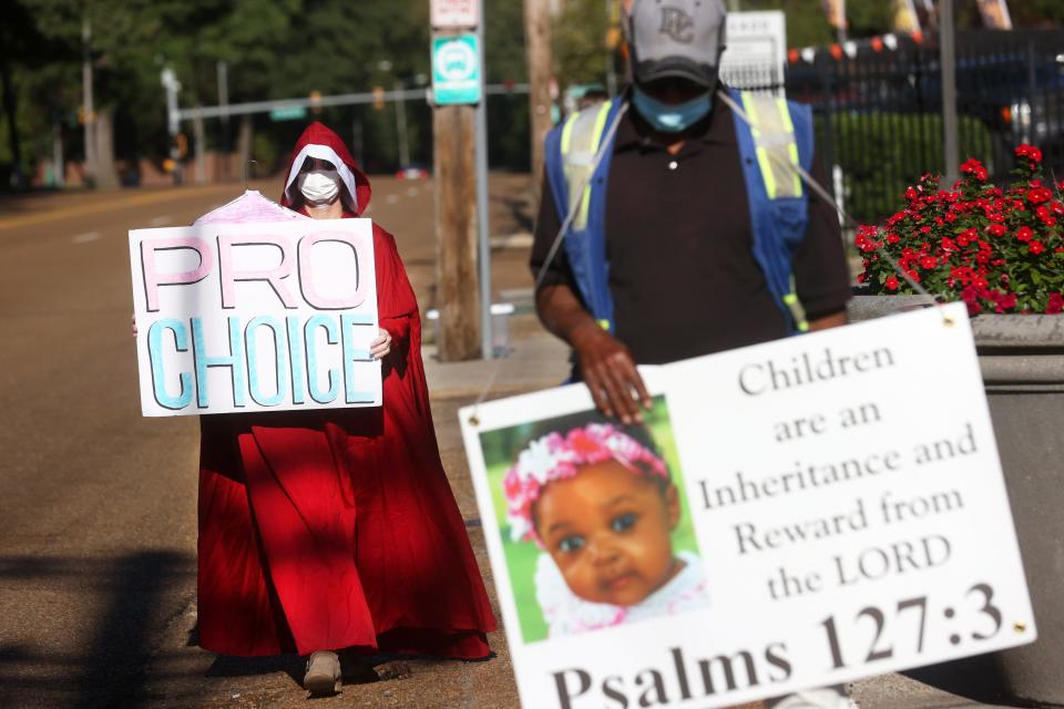 Dressed as a character from the Handmaid's Tale, a woman going by the name 'June' to protect her identity, rallies for pro-choice rights outside of Planned Parenthood next to William Winfrey who, alternately, is protesting against abortions on Wednesday, Sept. 22, 2021. 'June' named the recent law in Texas calling for abortions to become illegal six weeks into a pregnancy as motivation for the demonstration. "We could be the same as Texas soon and we, as women, could have our rights taken away from us," she said.