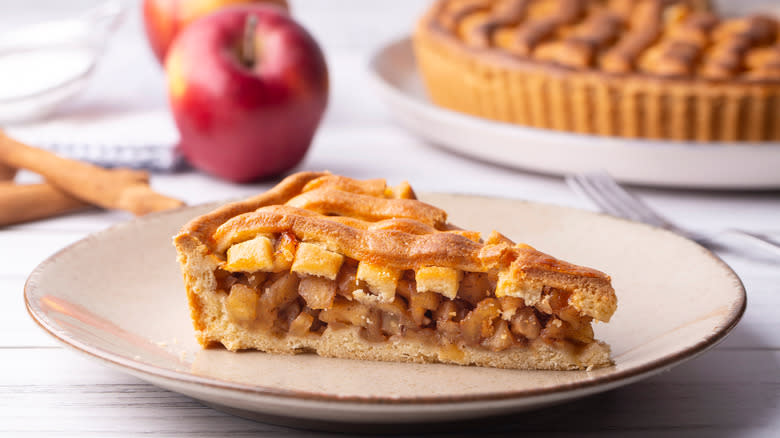 Slice of apple pie with apples in background