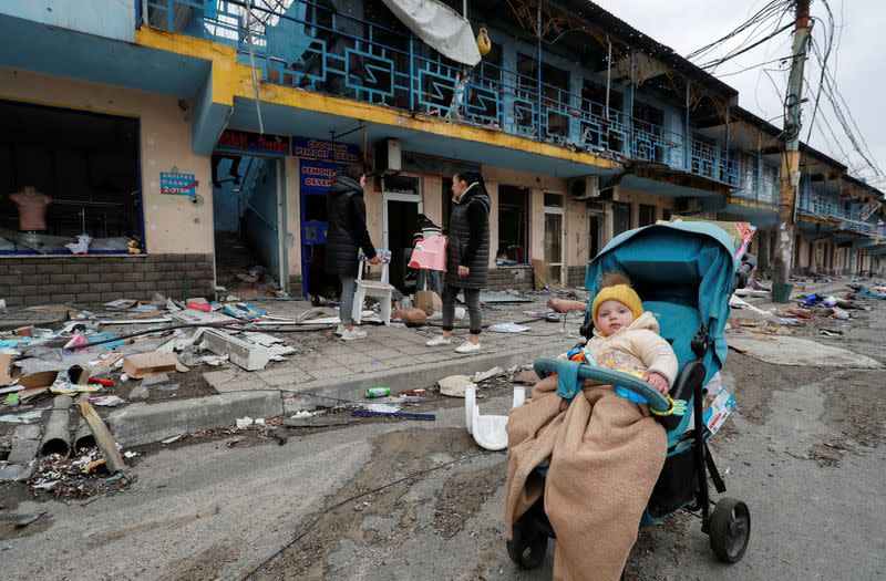 People gather outside a destroyed shopping centre in Mariupol