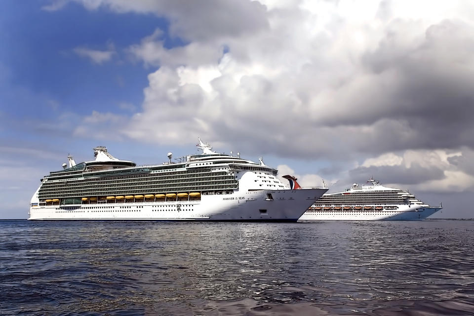 Cruise ships anchored off the shore of Grand Cayman Island, Royal Caribbean Caribbean cruise liner, Mariner of the Sea and Carnival Cruise Liner, turning to return to sea. 