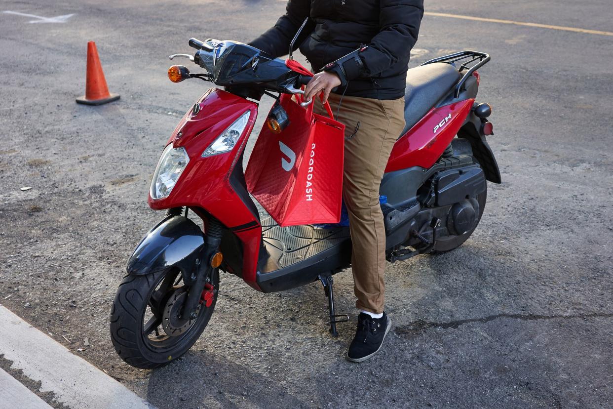 San Francisco, CA, USA - Feb 8, 2020: A DoorDash delivery worker on his motorcycle in the SoMa neighborhood of San Francisco, California.