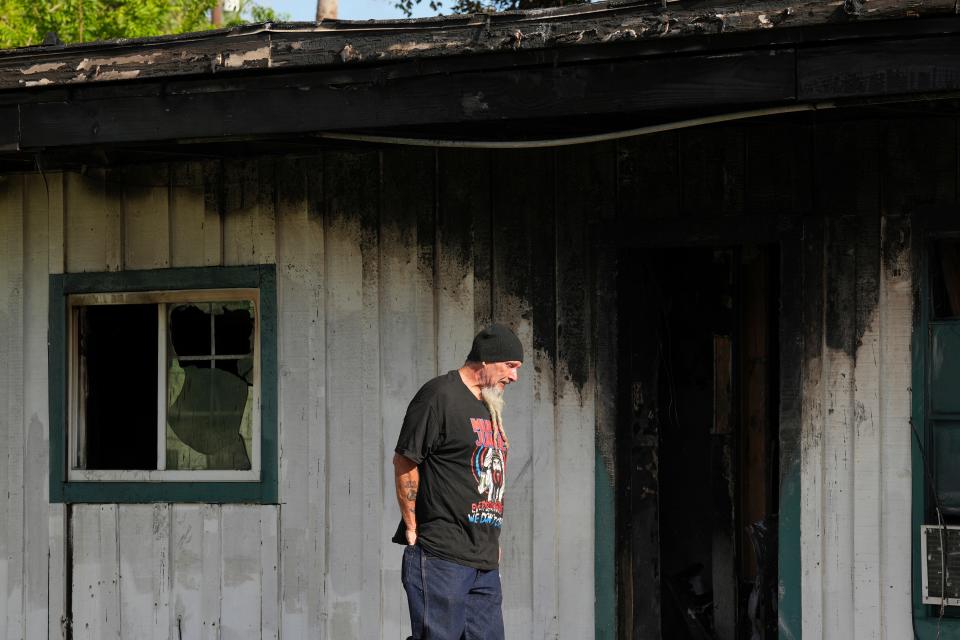 Robin Ahrens, a resident of a multi-room renting facility, walks past the burned out building in the aftermath of a fatal shooting in Houston on Sunday, Aug. 28, 2022. A longtime tenant started several fires at the site early Sunday and then shot at residents as they fled the blaze, before authorities fatally shot him, police said. (Brett Coomer/Houston Chronicle via AP)