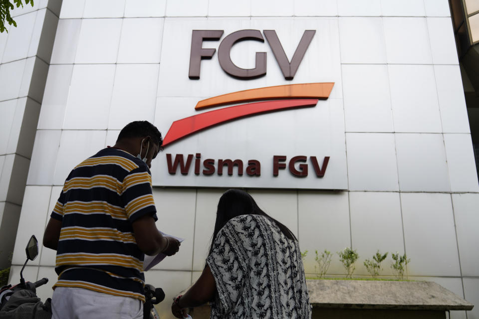 A couple talks outside FGV Holdings Berhad, one of Malaysia's largest palm oil companies, in Kuala Lumpur, Thursday, Oct. 1, 2020. Malaysian palm oil producer FGV Holdings Berhad vowed Thursday to “clear its name” after the U.S. banned imports of its palm oil over allegations of forced labor and other abuses. (AP Photo/Vincent Thian)